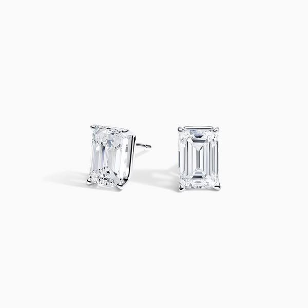 Reference: two emerald-cut diamond studs, plain white background, even light